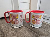 Front view of both travel mugs showing graphics and bases