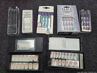Overview of eight false-nail kits laid out on carpet