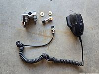 CB microphone handset with coiled cord and mount hardware on concrete surface