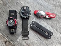 All four items grouped: two watches, red utensil tool, black pliers tool