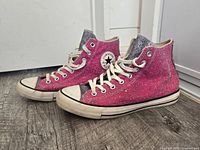 Left side view of pair showing pink glitter uppers, ankle patch, sole wear