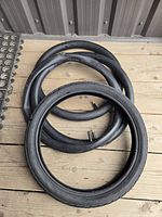 CST bicycle tire and three inner tubes displayed on wooden deck