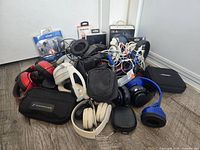 Pile of assorted headphones, earbuds, cases and retail packages