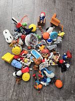 Pile of assorted small figurines and toy accessories spread on floor