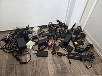 Overview of large assortment of laptop adapters and cords spread on floor