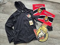 group shot showing hoodie, two towels, playing cards deck and aluminum sign