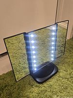 Mirror open with LEDs lit, showing tri-fold design