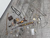 Entire lot spread out showing necklaces, bracelets, pendants, keychains, scapular, figurines