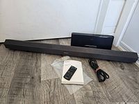 Soundbar, SoundDock speaker, remote, manual, power cable displayed on floor
