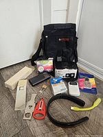 Group shot of all travel accessories including shoulder bag, binoculars, locks, power bank, radio, wipes, key, USB lamp, neck band