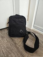 Front view of black Reebok bag showing logo and zip pockets
