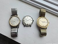 All three watches side by side showing faces and bands