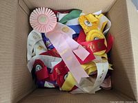 Box filled with various coloured rosette and flat ribbons