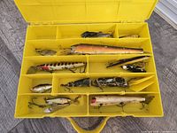 Lures stored in yellow tackle box showing compartment layout and contents