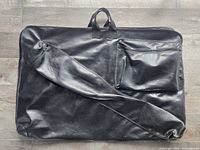 Front of black portfolio showing carry handles, long zippered compartment and smaller zippered pocket