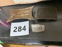 Three belt buckles arranged on surface showing designs