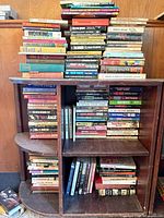 Full view of bookcase loaded with books and additional stacks on top
