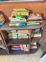 Overall view of small wooden bookcase filled with stacked and shelved books
