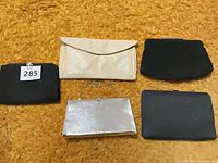 Five small clutch purses arranged on surface showing colors and styles