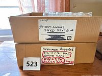 Two stacked boxes labeled for glass jars and specimen bottles showing clear glass containers inside