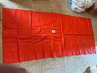 Deflated red vinyl inflatable mattress laid flat