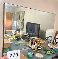 Full view of frameless rectangular mirror with clips, items reflected