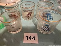 Five vintage horse-racing themed rocks glasses on table