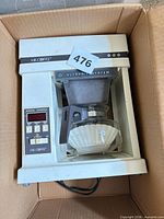 Full view of coffee maker inside box showing carafe, basket, control panel