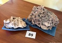 Both mineral specimens on blue cloths side by side
