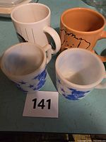 Four mugs arranged on tabletop