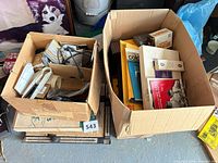 Two boxes filled with assorted darkroom items and glass frame nearby