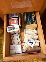 Drawer view showing multiple playing card decks, poker chip box, tin, unidentified white wrapped decks