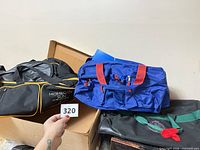 All three bags in box: black Mohegan Sun duffle, blue duffle, black carryall