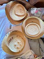 Three straw sun hats displayed on bed
