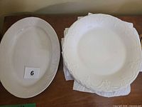 Stack of twelve dinner plates next to oval platter