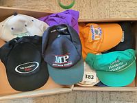 Box containing six Haskell Stakes promotional baseball caps