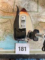 Top view of Valiant chrome travel iron showing label, folding handle and cord