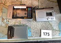 Panasonic cassette player in case, RadioShack microcassette recorder, Sony pocket radio displayed on map surface with lot number