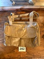 Front of black leather shoulder bag showing flap pocket and embossed logo