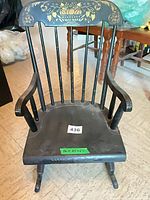 Front view of black child rocking chair with gold stencil and lot tag