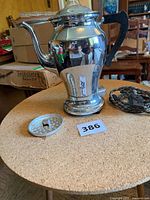 Full view of chrome Universal percolator with cord, glass knob and perforated lid on tabletop