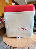 Front view of white Gott Tote 18 cooler with red lid and printed logo