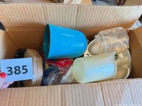 Open box showing plastic cups, citrus juicer top, measuring spoons, wood coasters