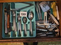 Drawer view showing flatware tray, tongs, whisks, spatula and mixed utensils