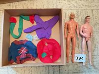 Box with five clothing pieces and two nude male dolls