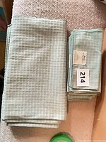 Folded tablecloth beside stack of eight napkins