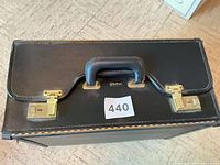 Top view showing handle, dual latches, leather-look surface, lot sticker