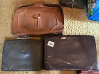 Three suitcases closed: tan, dark green, dark brown