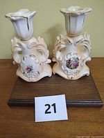 Front view of both ceramic candlestick holders showing floral decals and gold trim