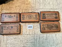 Five rectangular wood plaques with vintage bank-note images laid out on floor, lot reference card visible